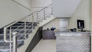 A reception area with a marble counter, a staircase with metal railings, and a door in the background.