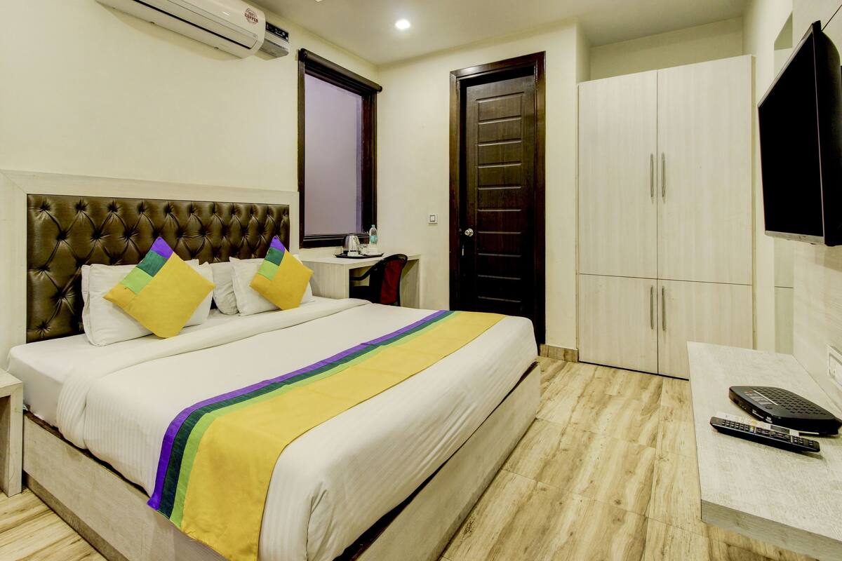 A hotel room with a bed, a desk, a wardrobe, and a television.