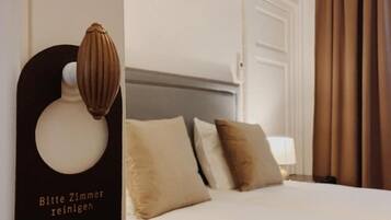 Een hotelkamer met een net opgemaakt bed, een kussen en een wandlamp.