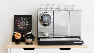 A Nespresso coffee machine with a digital interface, a coffee grinder, and a menu display on a wooden countertop.