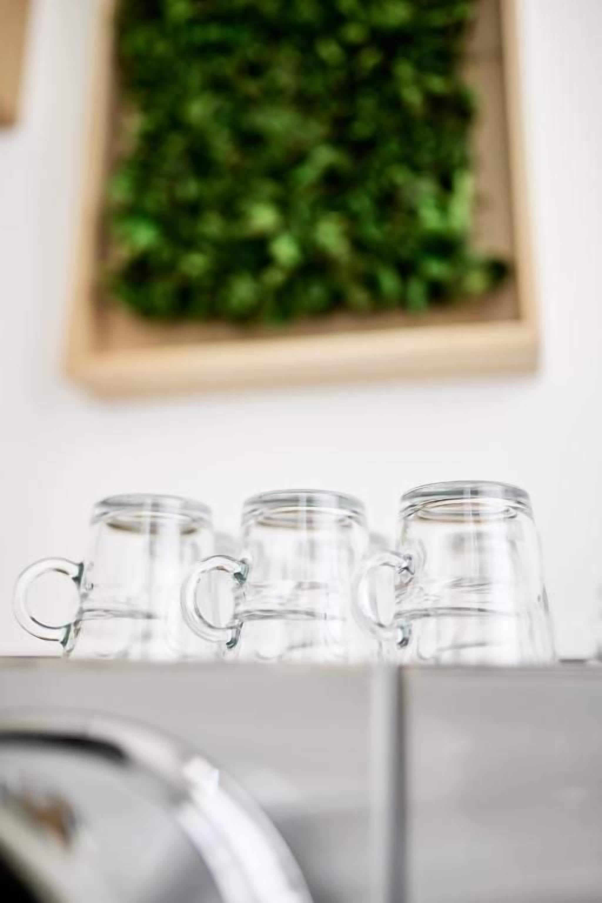 A kitchen area with a stainless steel range hood and three clear glass mugs on a shelf.