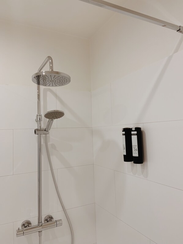 Une douche équipée d’un pommeau de douche à main et d’un robinet fixé au mur.