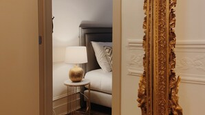 Une chambre à coucher comprenant un lit, une table de chevet, une lampe et un grand miroir décoratif.