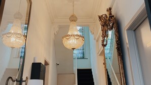 Un vaste hall d’entrée orné de lustres somptueux, avec un escalier et un grand miroir.