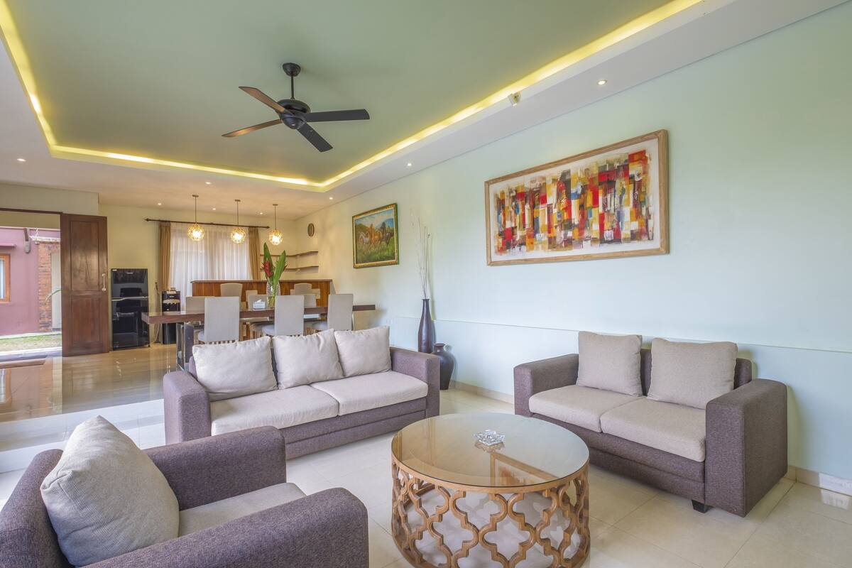 A spacious living room with two sofas, a coffee table, and a ceiling fan.