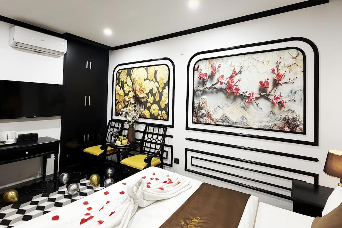 A modern bedroom with a bed, a desk, and two paintings on the wall.