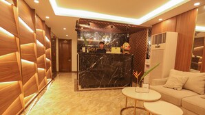 Ein Hotel-Empfangsbereich mit Marmor-Theke, Holzvertäfelung, einem Empfangstresen, einer Couch und einem kleinen Tisch.