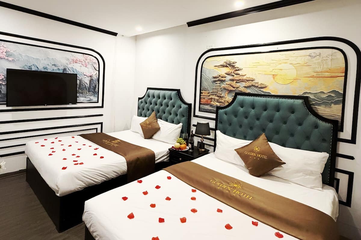 A hotel room with two beds, a TV mounted on the wall, and artwork depicting a landscape.