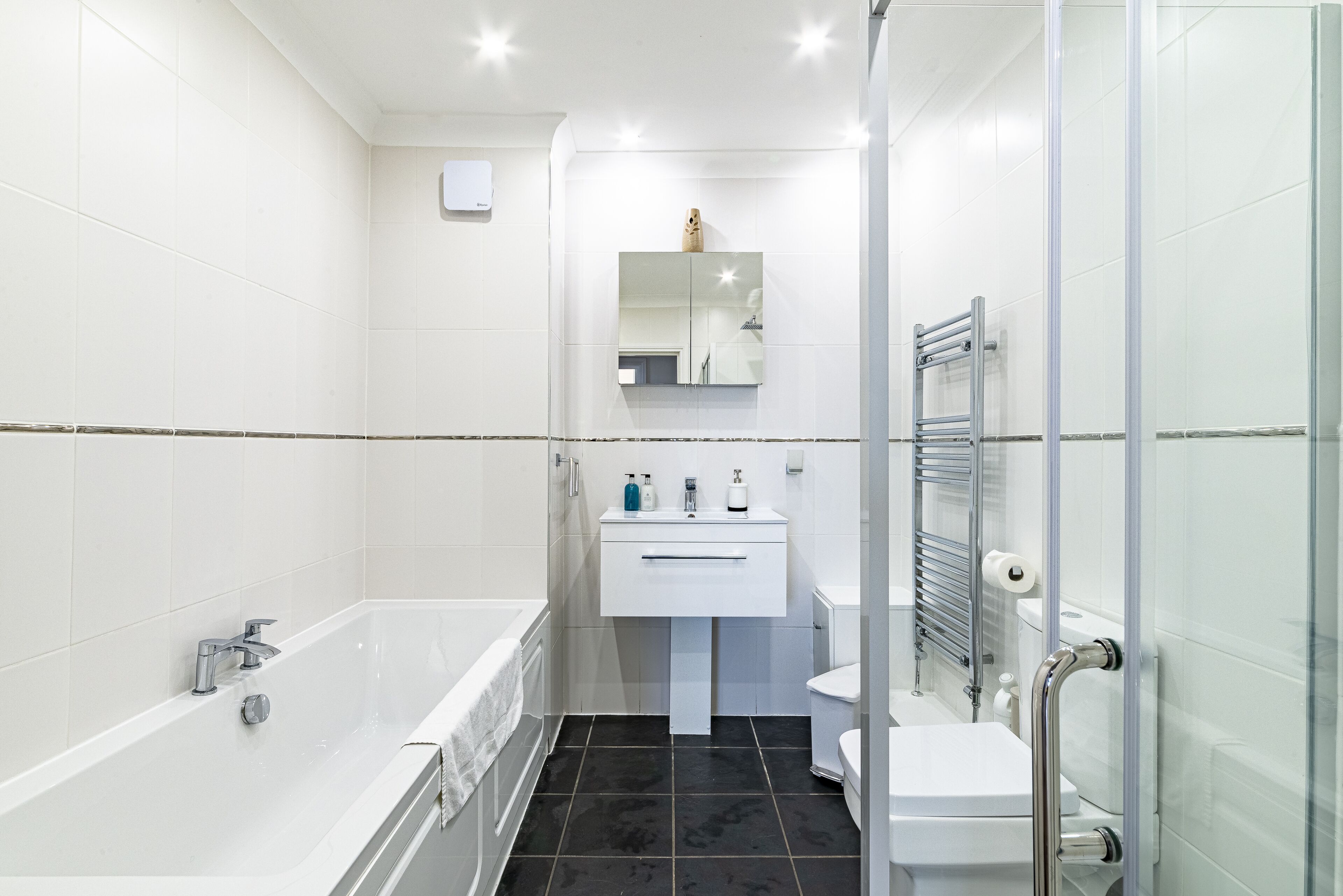 A modern bathroom with a bathtub, white sink, and glass shower enclosure.