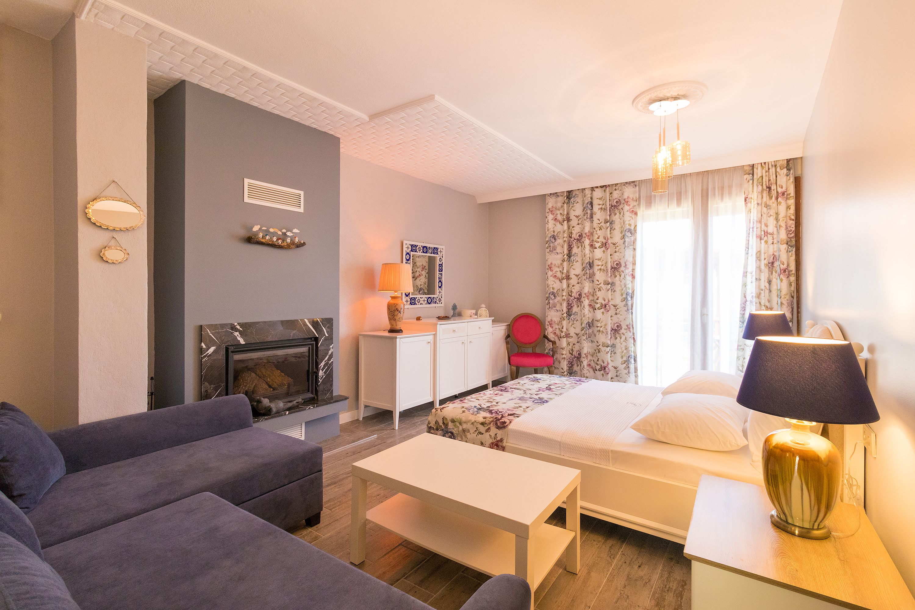 Una habitación de hotel moderna con sofá, cama, escritorio y chimenea.