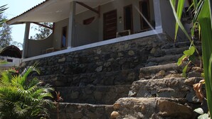 A house with a stone staircase leading to a porch with a white roof. - Join Homestay (Kuta)