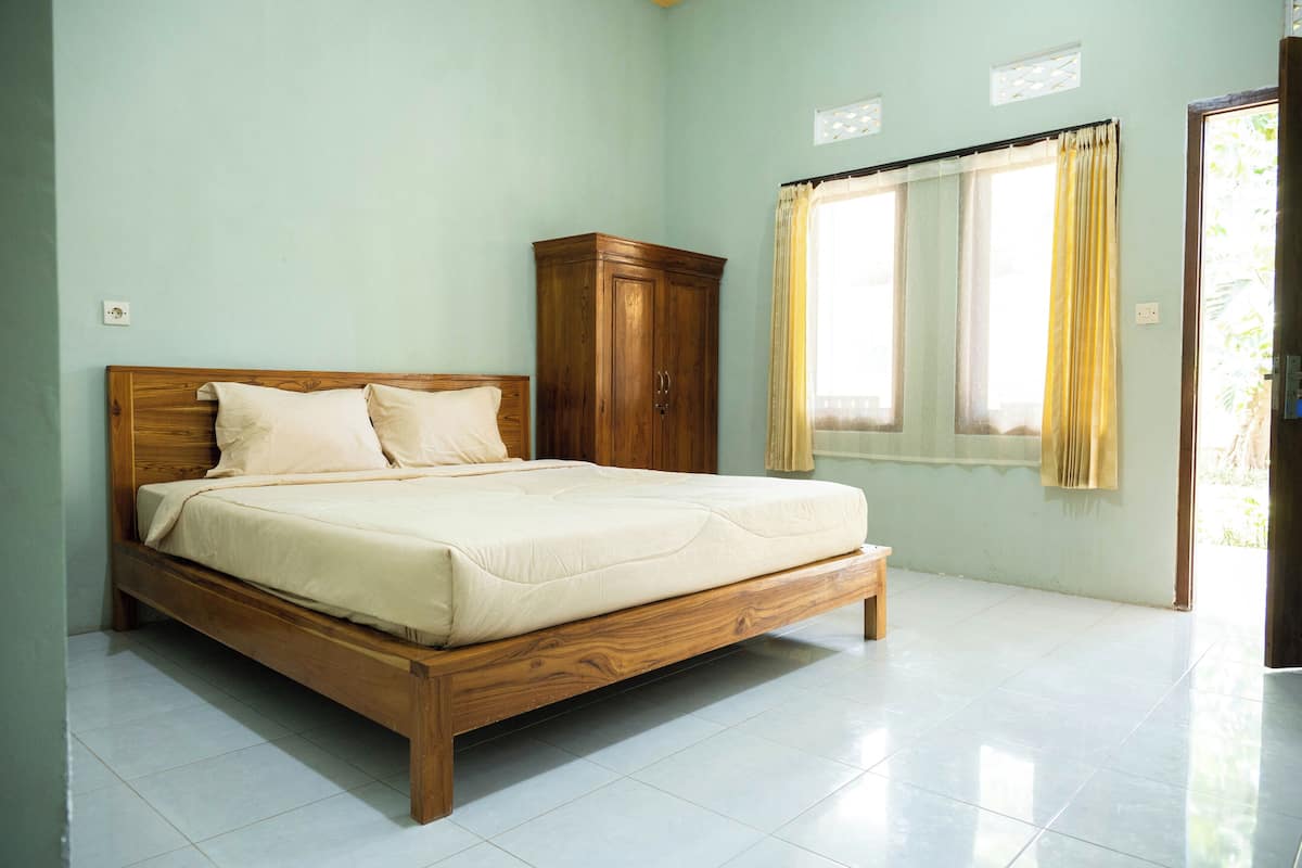 A bedroom with a wooden bed, a wardrobe, and a window with curtains.
