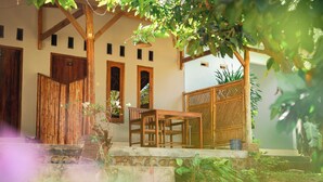 A wooden building with a staircase leading to a porch, a table, and a covered seating area. - Join Homestay (Kuta)