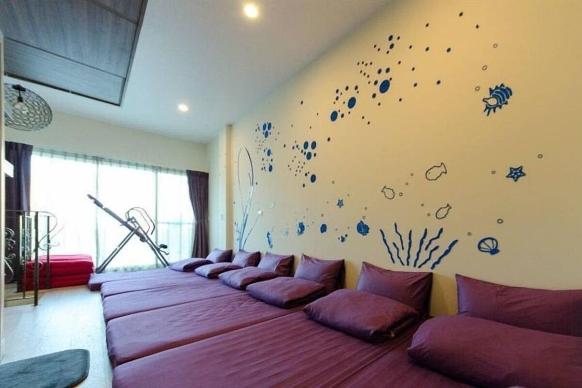 A hotel room with a large bed, a desk, and a chair. There is a window with curtains and a view of the outside.