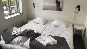 A hotel room with a bed, a window, a bedside table, and a wall-mounted artwork. - Hotel Crone (Grenaa)