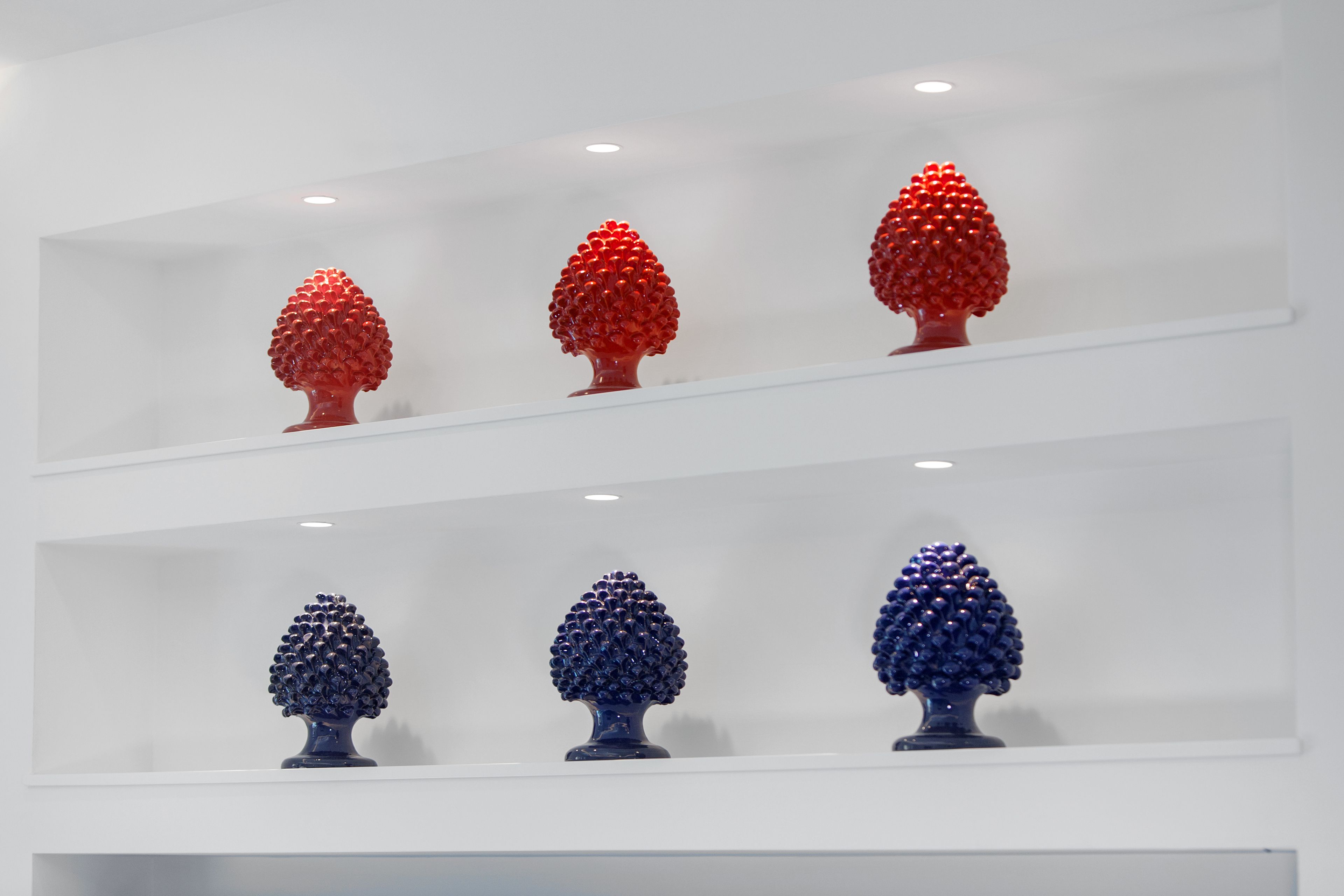 Une exposition d’objets sphériques rouges et bleus, présentés sur des étagères.