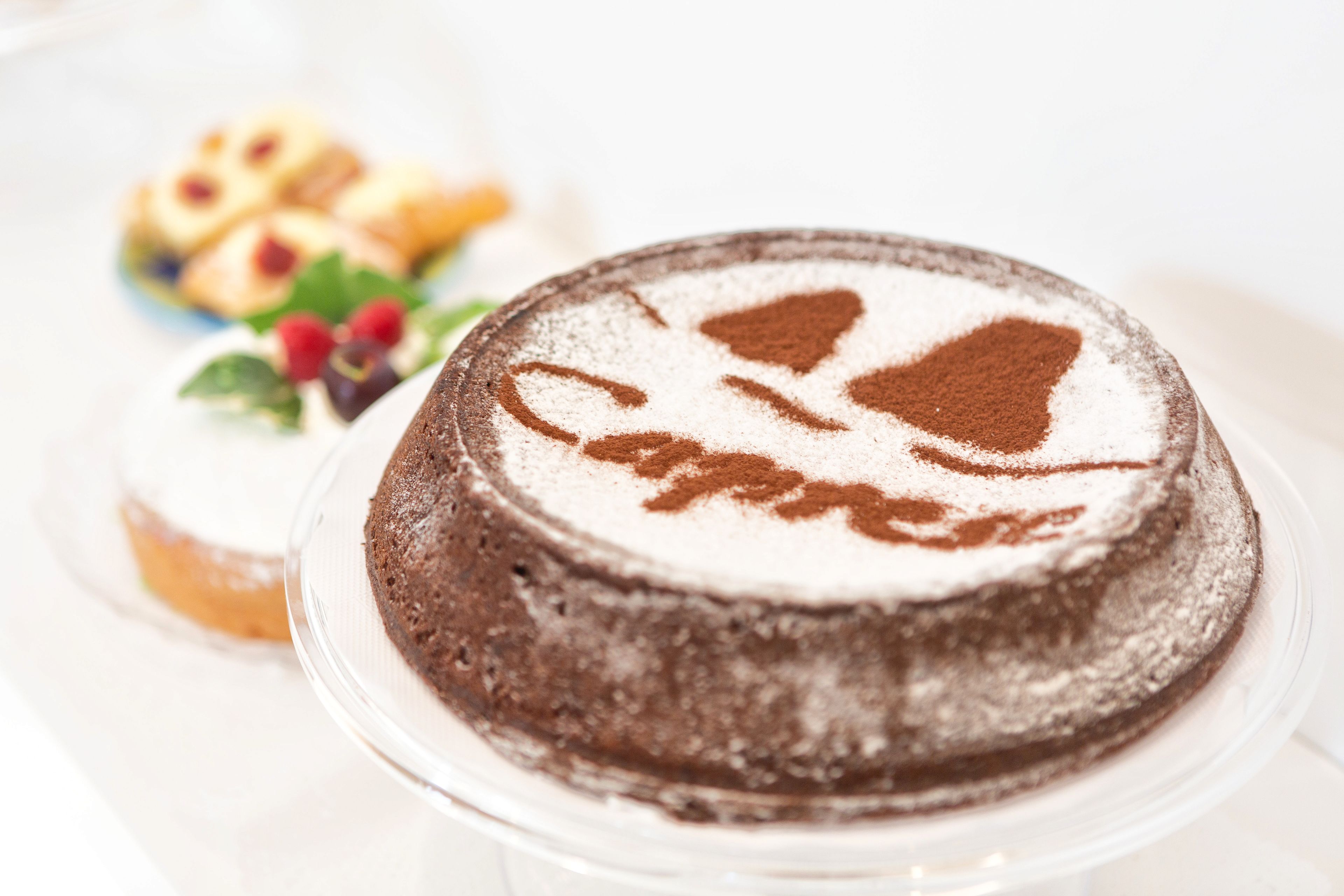 Un gâteau au chocolat décoré de sucre glace, présenté sur une assiette en verre transparente.