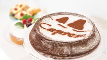 Un gâteau au chocolat décoré de sucre glace, présenté sur une assiette en verre transparente.