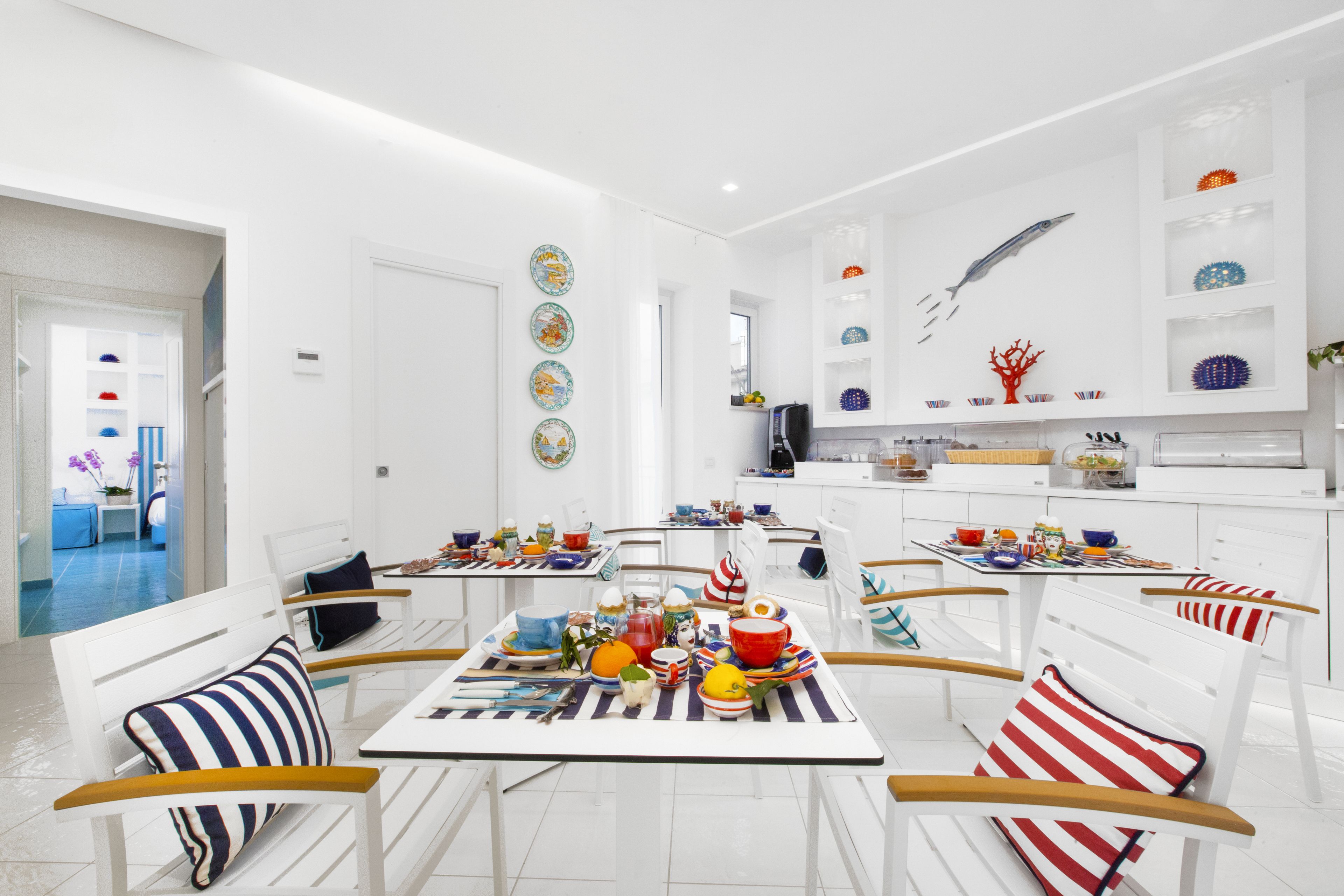 A modern kitchen with white cabinetry, a dining area with striped chairs, and decorative plates on the walls.