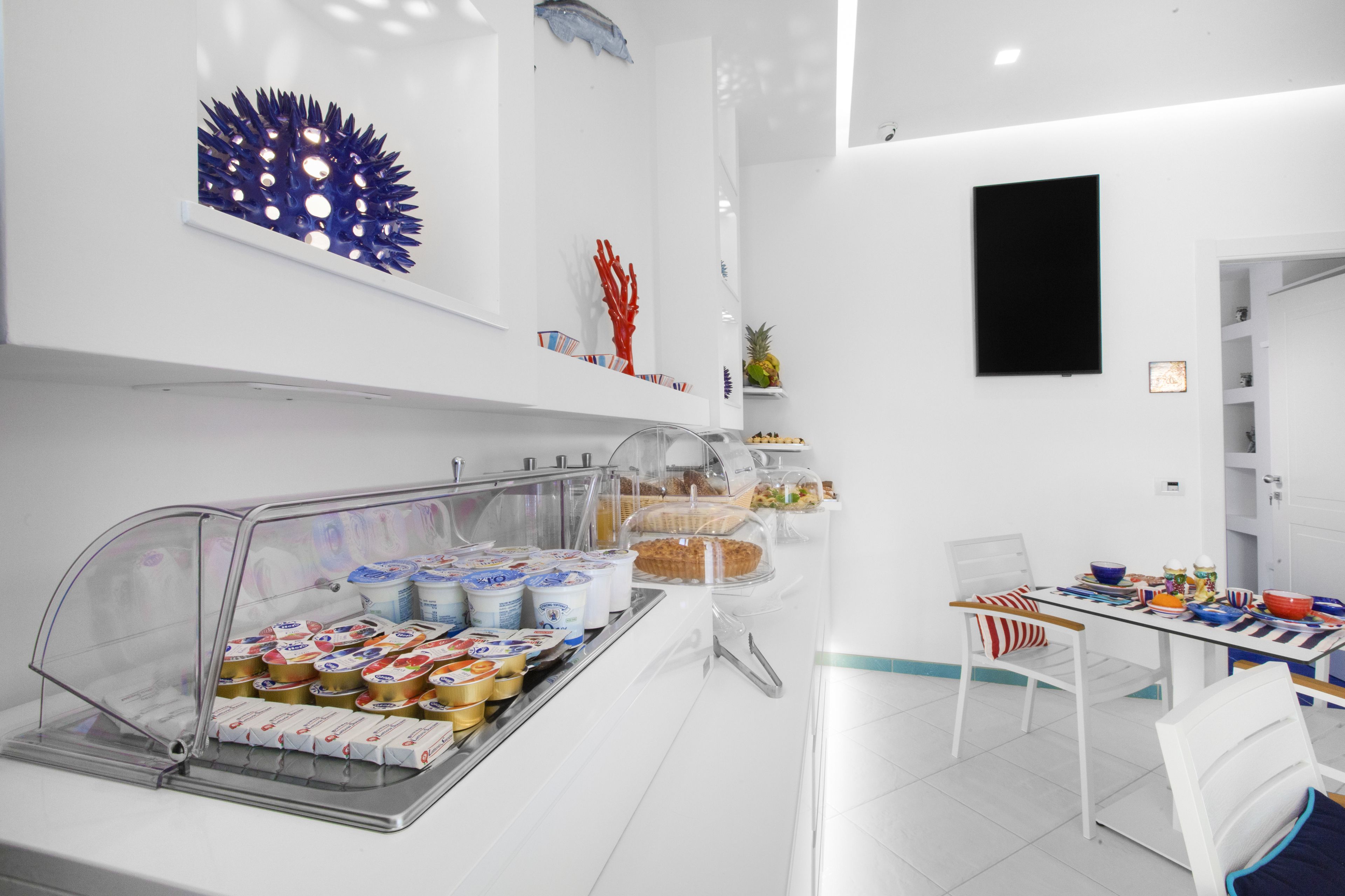 A breakfast area with a buffet, white walls, and a ceiling fan.