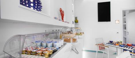 A breakfast area with a buffet, white walls, and a ceiling fan.