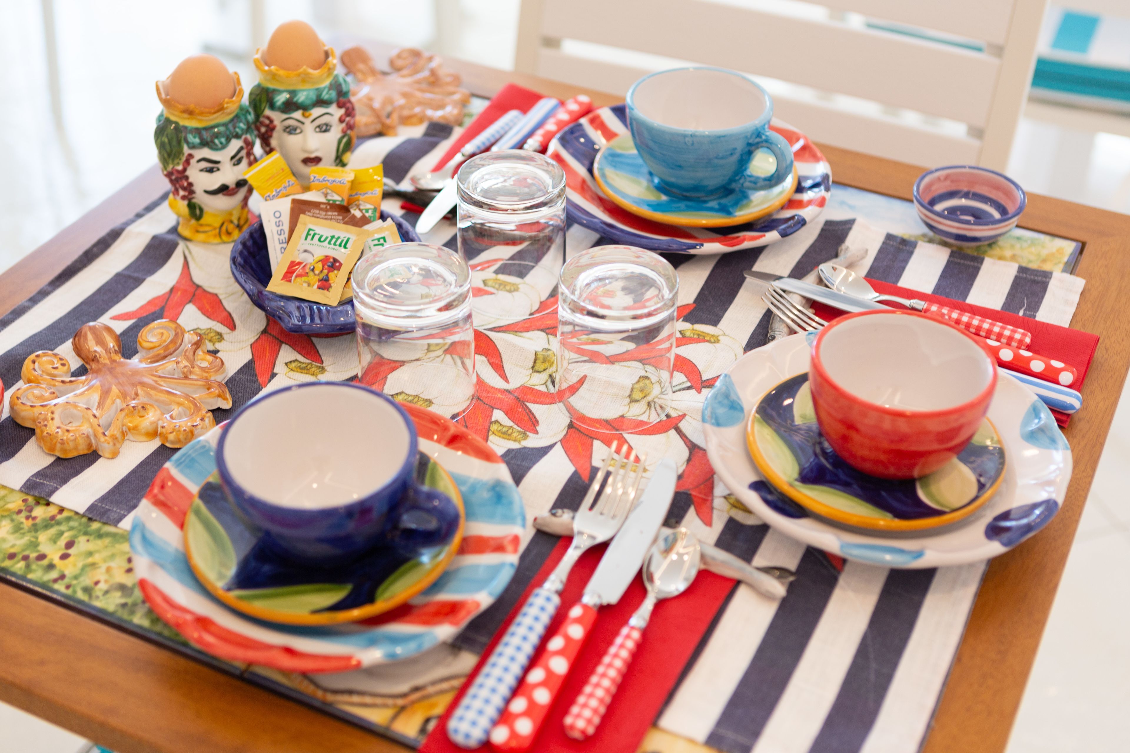 A table set with colorful plates, cups, and cutlery, along with decorative items and a striped tablecloth.