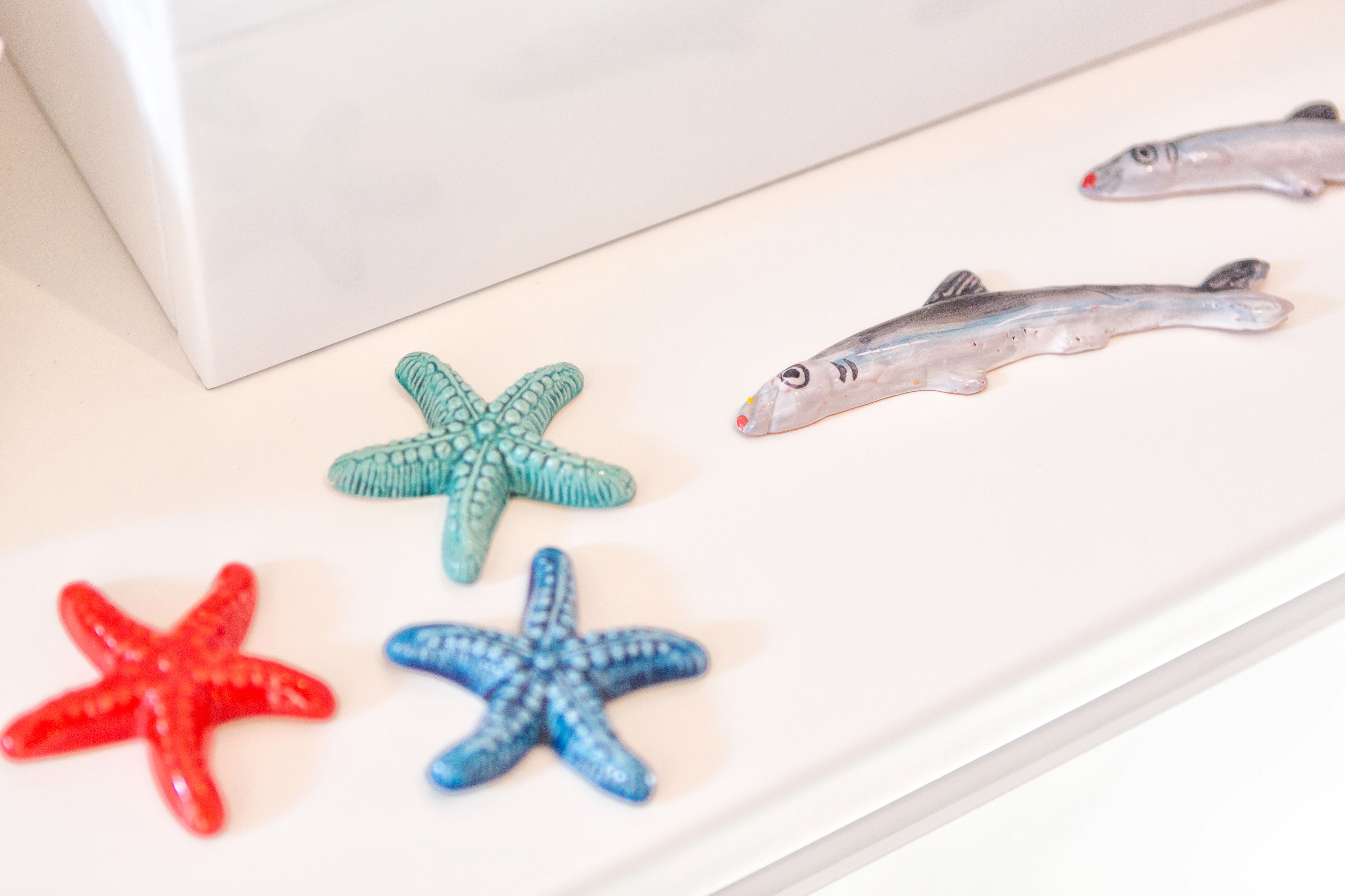 A white surface with four starfish and two fish toys.