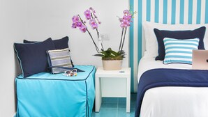 Un dormitorio con cama, una mesita, un banco y una orquídea en maceta.