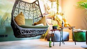 A hanging chair with cushions, a small table with a bottle, and a decorative plant. - EchtZeit - Dein Hotelquartier (Braunlage)