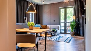A modern living room with a dining area, a sofa, and a large window with curtains. - EchtZeit - Dein Hotelquartier (Braunlage)