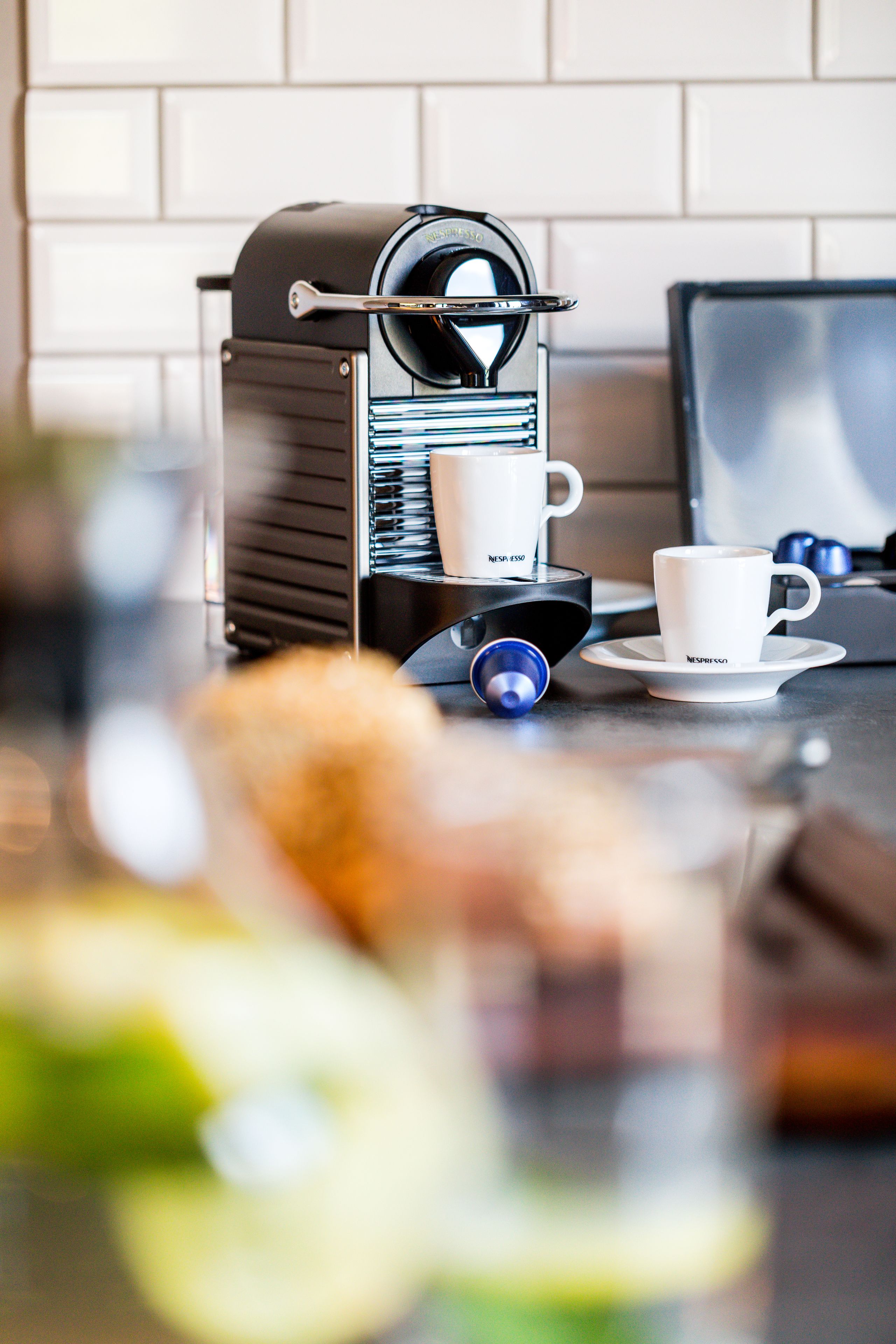 A coffee machine with a cup and saucer, a smartphone, and a blurred background.