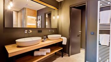 A modern bathroom with two large sinks, a wooden vanity, a large mirror, and a towel rack.