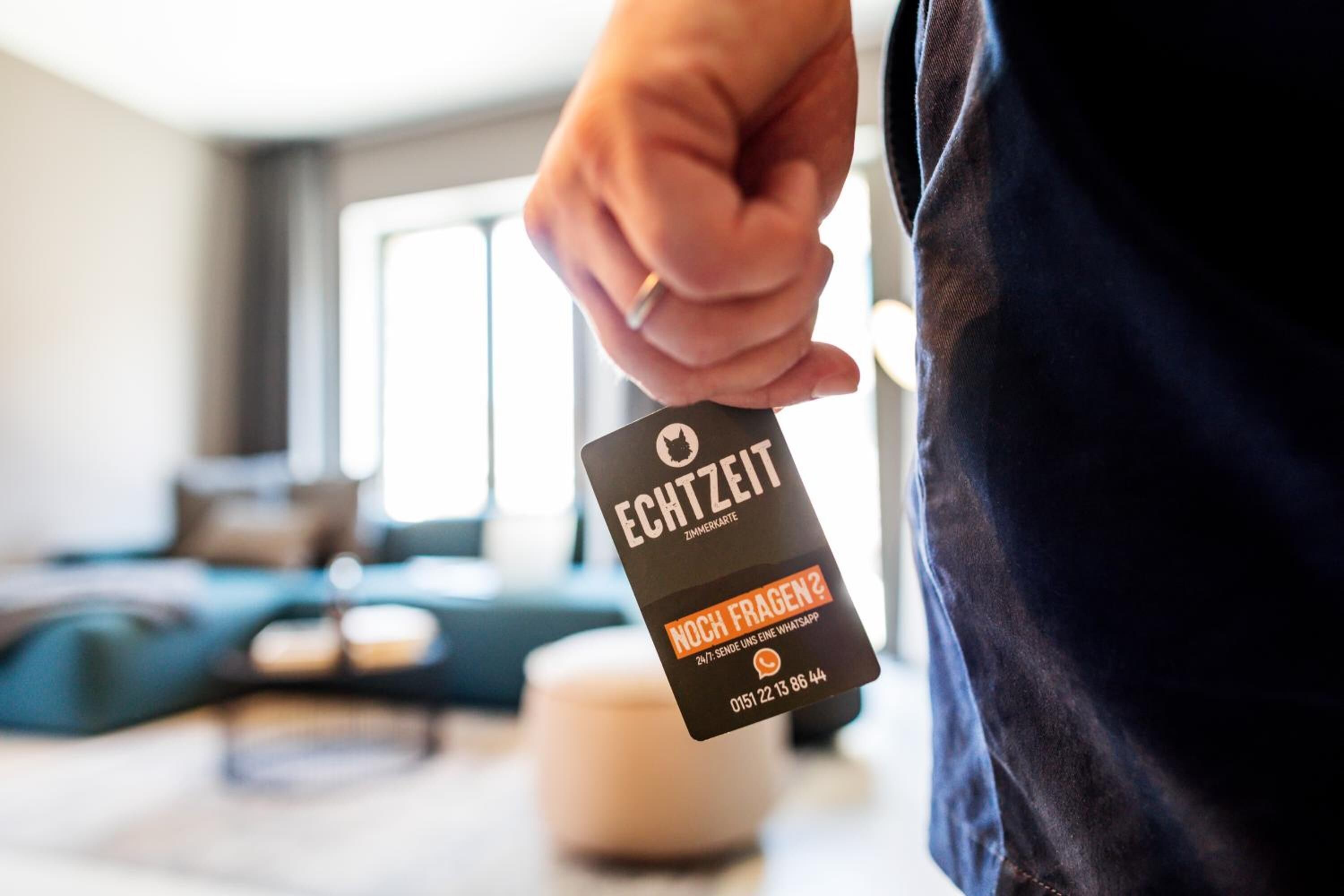 A person holding a black card with white and orange text, likely a hotel or service card.
