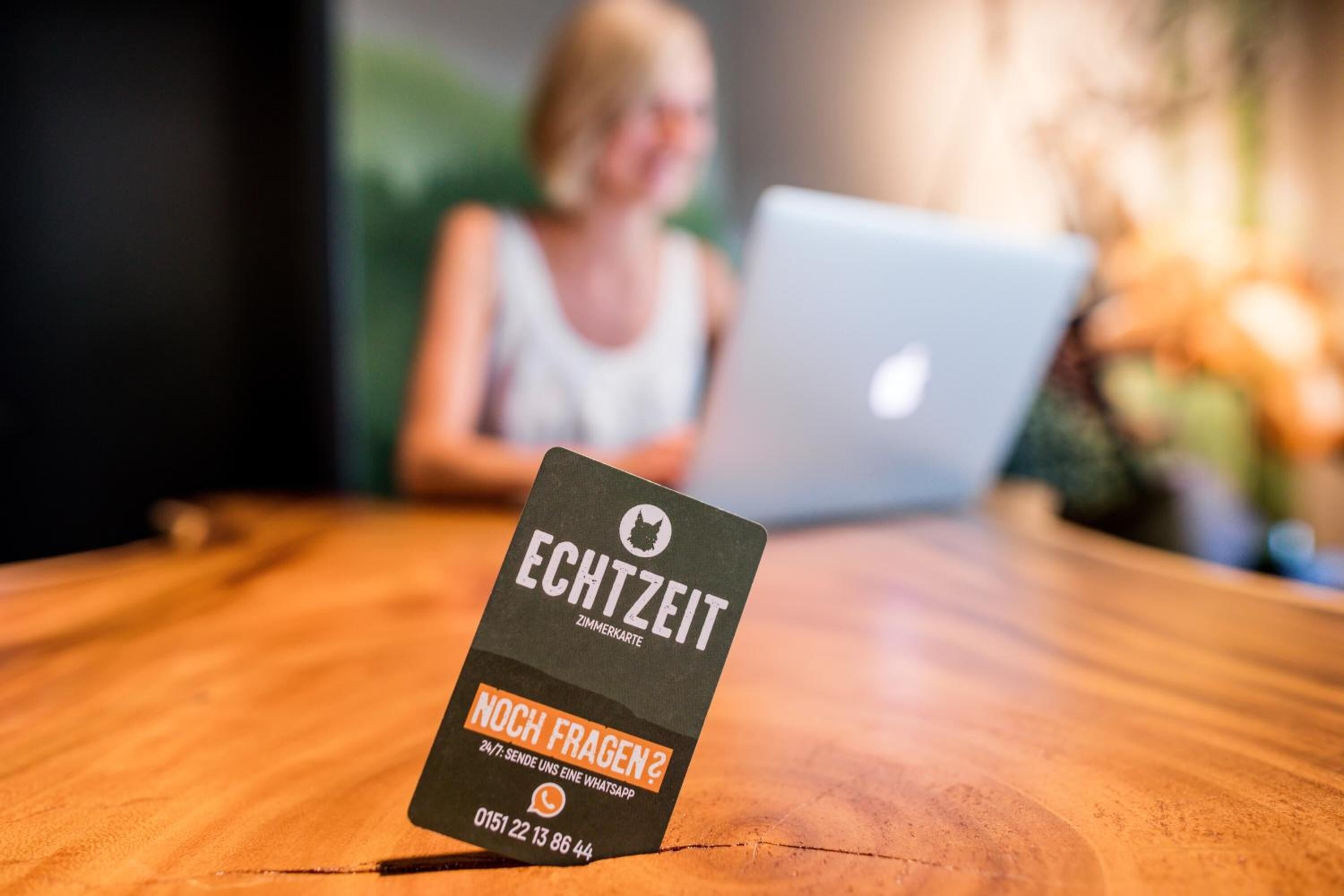Ein Holztisch mit einer Visitenkarte für 'ECHTZEIT', die deutlich sichtbar ist.