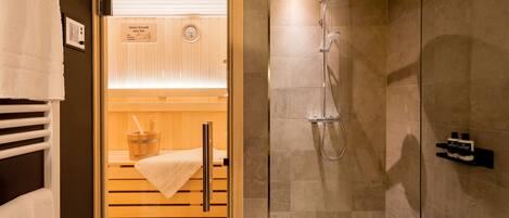 A sauna room with a wooden bench, a towel, and a sign indicating the sauna's temperature.