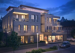 A modern multi-story building with balconies, large windows, and a well-lit facade. - EchtZeit - Dein Hotelquartier (Braunlage)