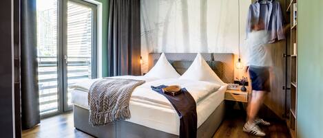 A modern bedroom with a large bed, a nightstand, and a wardrobe.