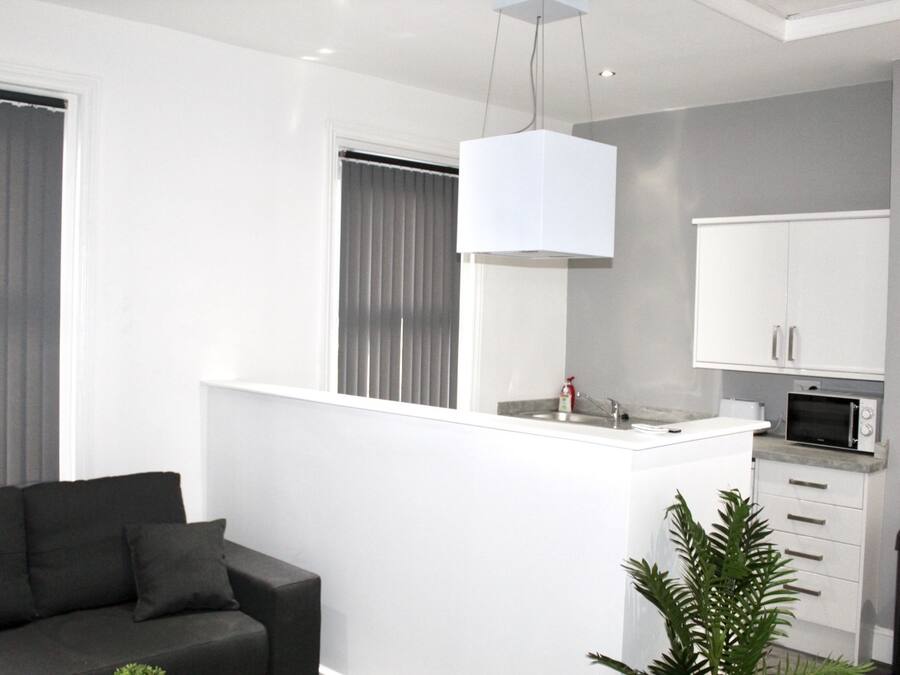 Een moderne keuken met witte kasten, een inbouwmagnetron en een hanglamp.