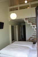 Quarto com uma cama grande, escada e luminária pendente.