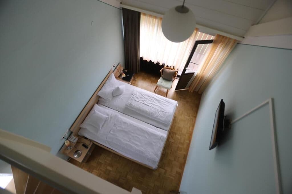 A hotel room with a bed, a chair, a desk, and a television.