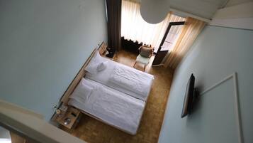 A hotel room with a bed, a chair, a desk, and a television.