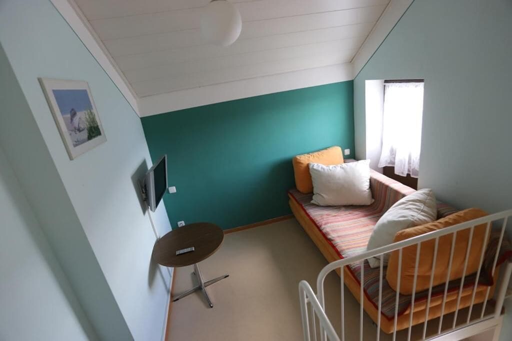 A small, single-room accommodation with a bed, a small table, and a window.