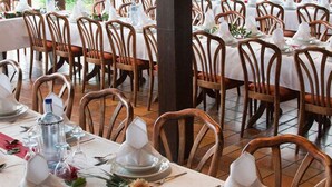 A dining area with multiple tables set for service, each with white tablecloths, wooden chairs, and neatly arranged table settings including plates, glasses, and cutlery. - Pension Krämerhof Kulz (Thanstein)