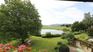 A view of a well-maintained garden with a pond, surrounded by lush greenery and flowering plants. - Pension Krämerhof Kulz (Thanstein)