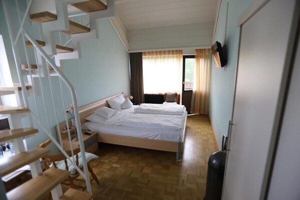 A bedroom with a bed, a TV, a desk, and a staircase. - Pension Krämerhof Kulz (Thanstein)