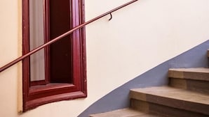 Eine Treppe mit einem hölzernen Geländer und einem Fenster mit rotem Rahmen.