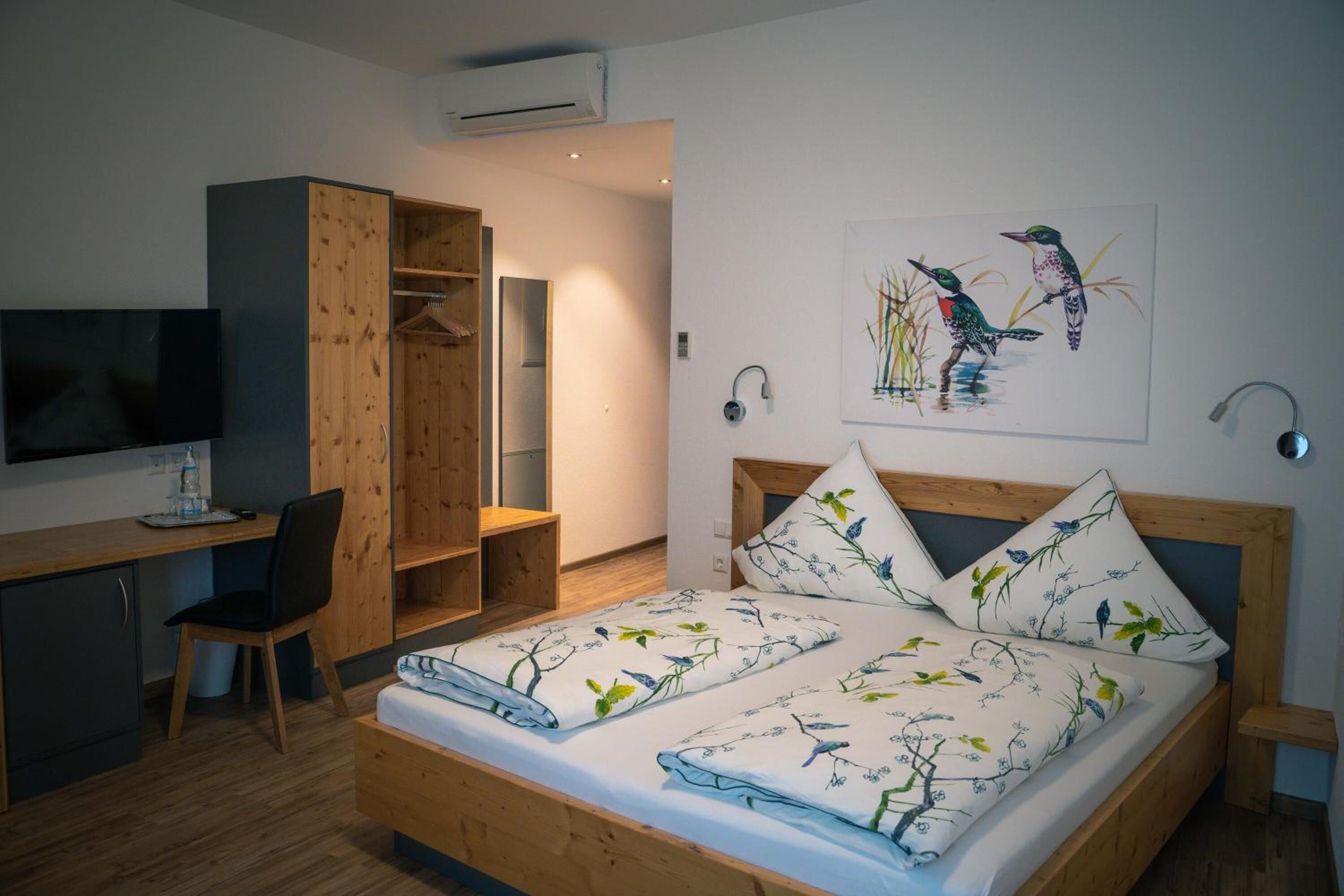 A bedroom with a bed, a desk, a chair, a TV, and a wardrobe.