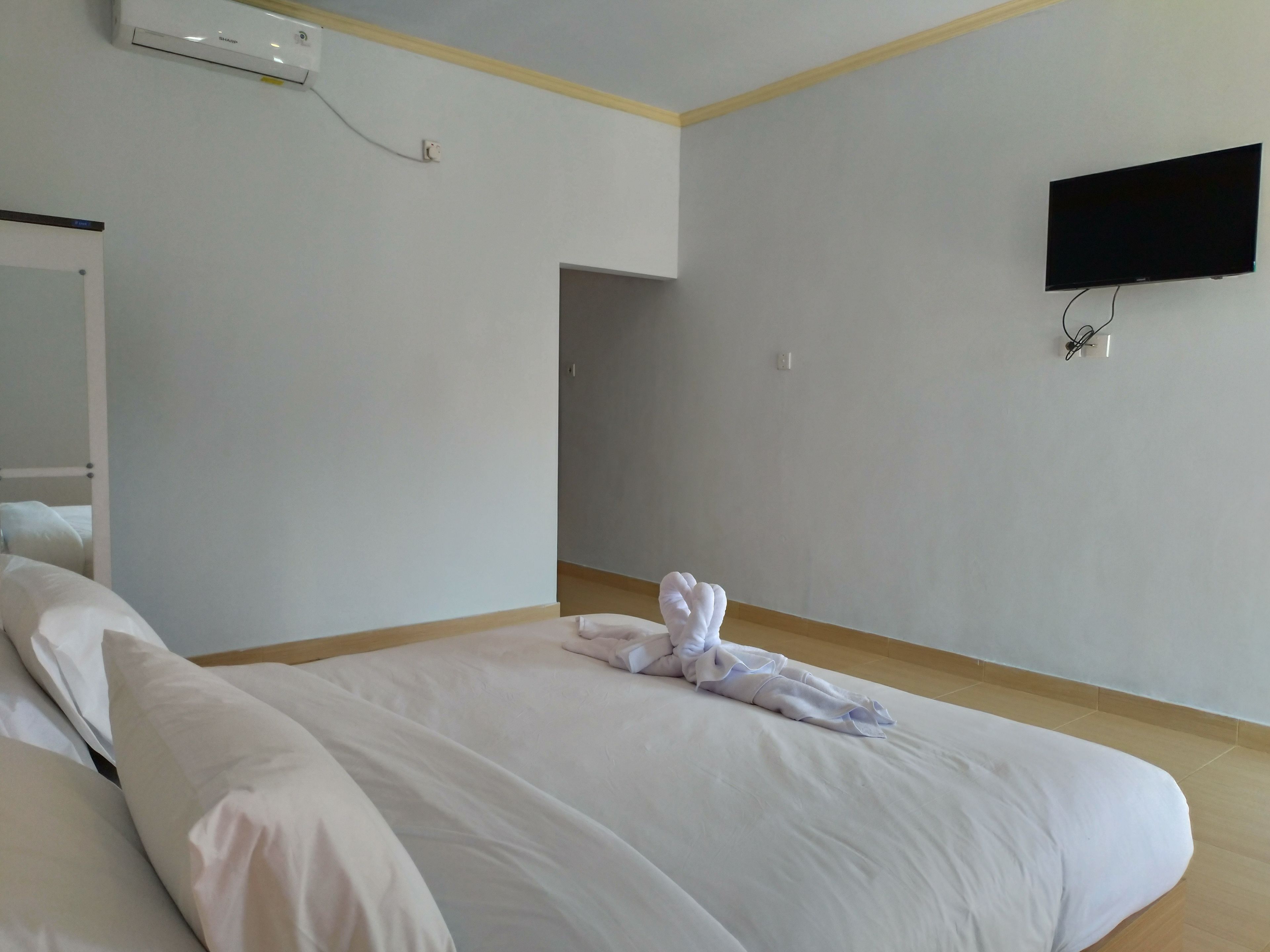 Une chambre d’hôtel équipée d’un lit, d’un téléviseur à écran plat fixé au mur et d’un appareil de climatisation visible.