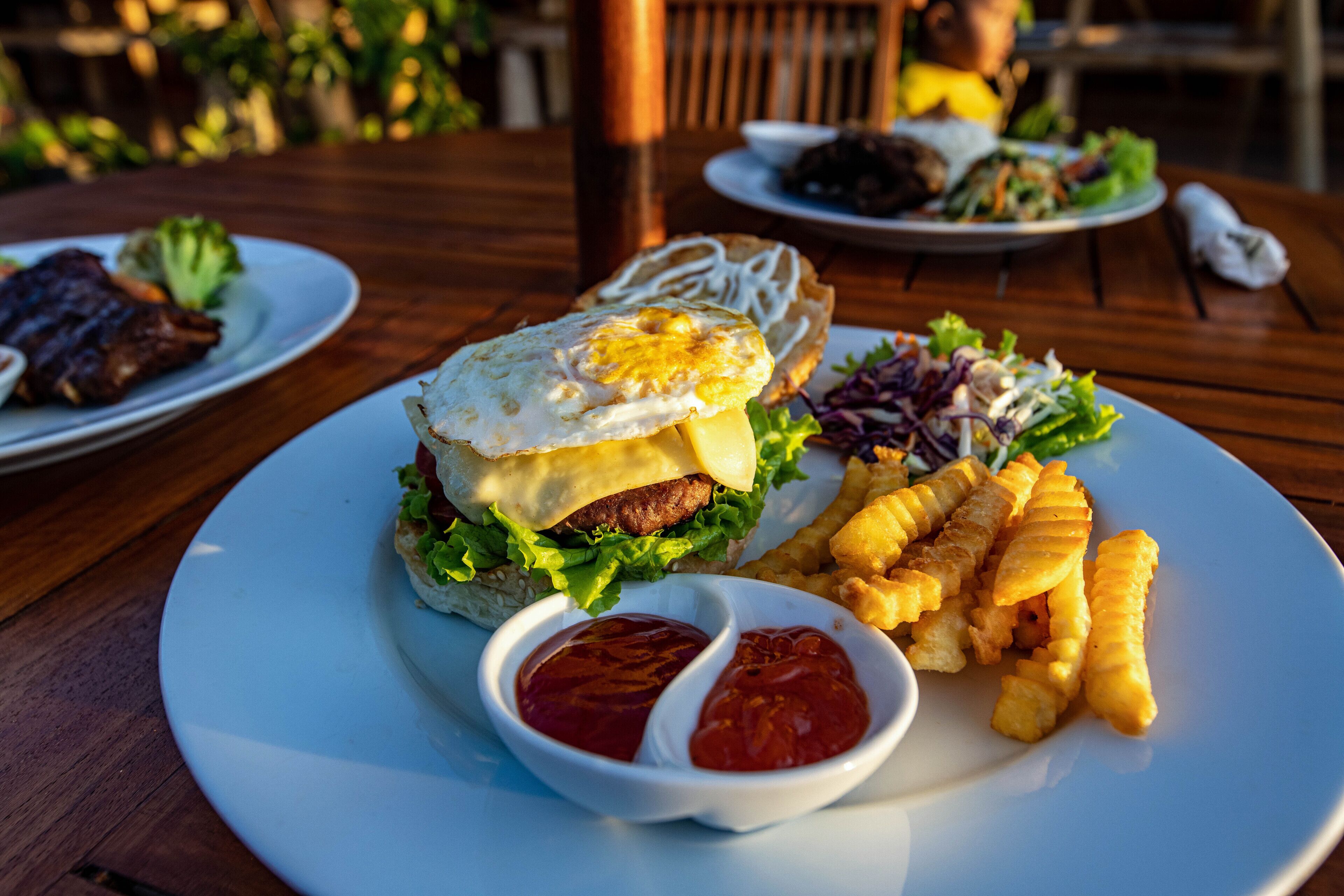 A plate with a burger, fries, and two sauces.