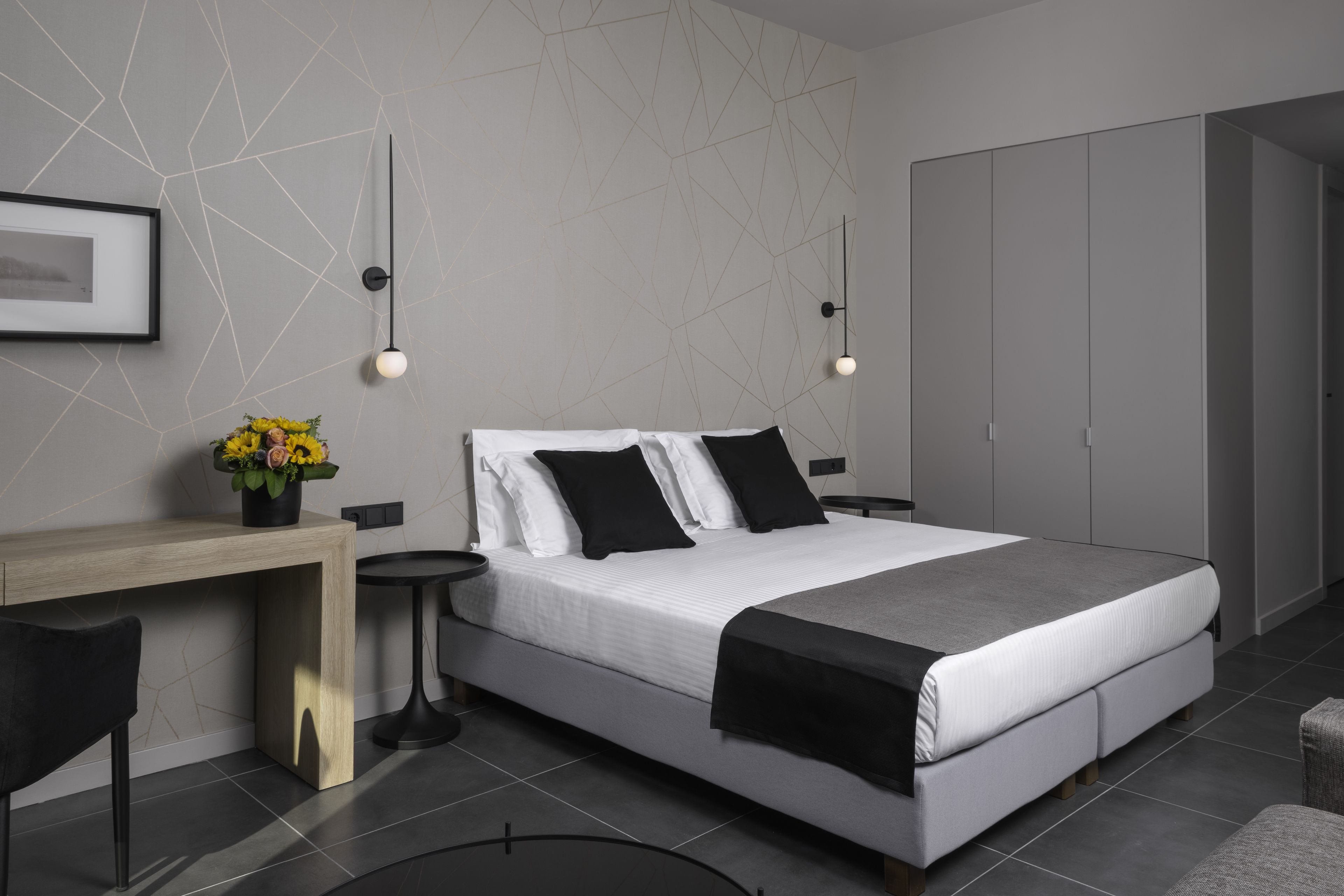 A modern bedroom with a bed, bedside tables, a desk, and a wardrobe.